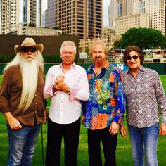 three men and one woman are standing in the grass with long white beards on