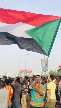 a large group of people standing around each other with flags flying in the air behind them