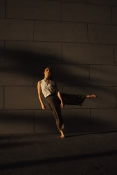 a woman standing on one leg in front of a wall