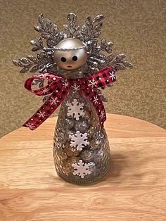 a silver and red snowflaked angel figurine sitting on top of a wooden table