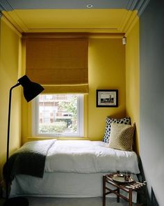 a bedroom with yellow walls and white bedding