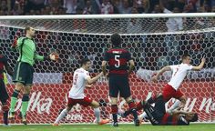 a group of men playing soccer against each other in front of a goalie net