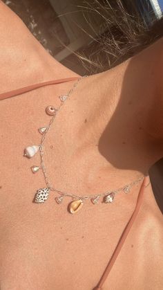 the back of a woman wearing a necklace with seashells on it