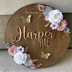 a wooden sign that says harper rae with flowers and butterflies around the letters on it