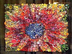 an art work made out of buttons and other items on a wooden surface, with the center surrounded by circles