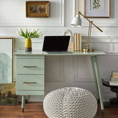 a laptop computer sitting on top of a desk next to a vase with tulips