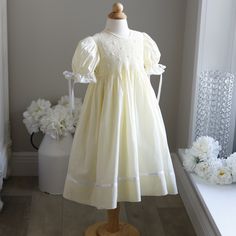 This Gorgeous Strasburg Pastel Pale Yellow Hand-Smocked Girls Float Style Dress Is In Perfect Condition. The Bodice Is Completely Hand Smocked In Yellow And White And Has White Embroidered Flower Details With Yellow Centers. The Gathered Puff Sleeves Are Trimmed In White Satin Ribbon Which Ties In A Bow And Are Finished Off With A Delicate Crocheted Cotton Lace. The Skirt Has A Lovely White Satin Ribbon Band With An Attached Delicate Crocheted Cotton Lace Trim. The Dress Is Fully Lined And Has A Button Back Closure With A Sash That Ties Into A Bow. Great For Weddings, Church, Portraits, Vacation Or Any Special Occasion. Matching Sister/Cousin Dresses Available In Sizes 6/9 Months, 24 Months Heirloom Dress Patterns, Matching Sisters, Heirloom Dresses, Hand Smock, Pale Yellow, White Satin, Cotton Lace, Embroidered Flowers, Satin Ribbon