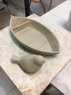 two clay boats sitting on top of a table next to each other, with one boat shaped like a bird