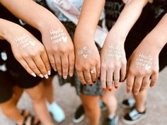 four girls with white tattoos on their hands are holding each other's hand together