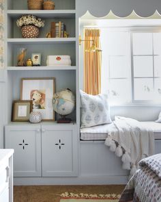 a window seat in a room next to a shelf with pictures and other items on it