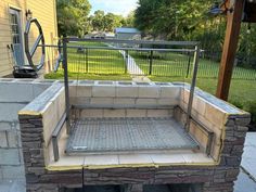 an outdoor fire pit built into the side of a house with metal bars on it