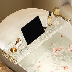 a bath tub with flowers on the floor and a laptop computer sitting on top of it