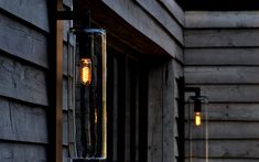 an old fashioned light is hanging on the side of a wooden building next to some lights