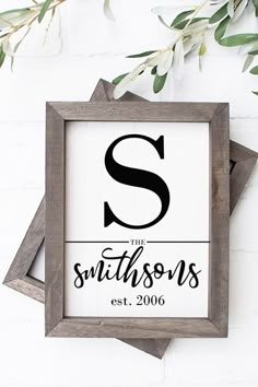 a wooden framed sign with the letter s in black and white, hanging on a brick wall