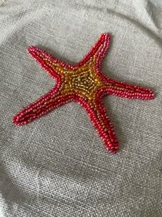 a red beaded starfish sitting on top of a piece of linen covered table cloth