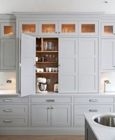 an open cabinet in the middle of a kitchen with white cupboards and counter tops