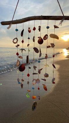 the sun is setting on the beach with shells hanging from it