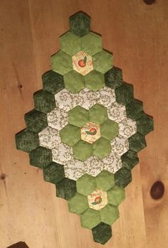 a green and white hexagonal quilt on a wooden floor