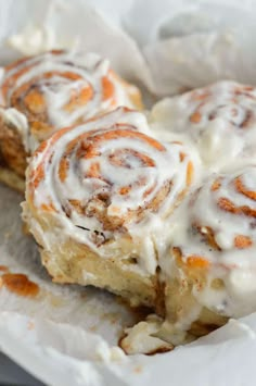 cinnamon rolls with icing sitting on top of white paper