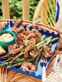 shrimp and asparagus on a blue platter with lemon wedges next to it