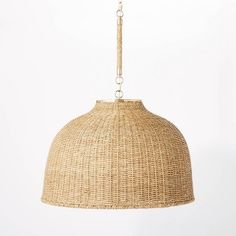 a large woven light fixture hanging from a chain on a white wall with no one around it