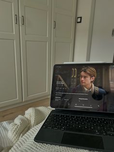 an open laptop computer sitting on top of a bed next to white cupboards in a bedroom