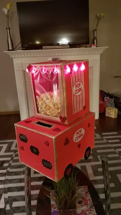 an open box sitting on top of a table with popcorn in it and lights coming from the inside