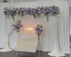 a white chair sitting under a purple flower covered arch