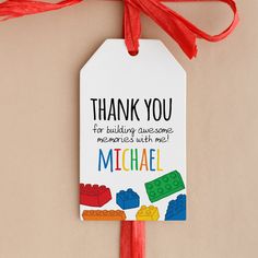 a thank you tag hanging from a red ribbon with legos and bricks on it