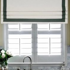 a kitchen window with roman shades over the sink