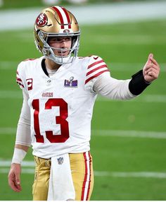 a close up of a football player on the field with his hand in the air