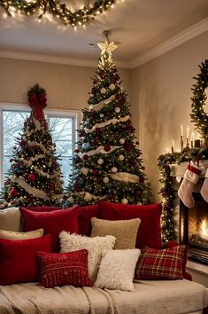 a living room decorated for christmas with red and white pillows on the couch, trees in the background