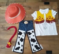 a cowgirl outfit and cowboy hat are laid out on a wooden floor next to a pair of jeans