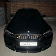 the front end of a black car parked in a parking garage with its hood up