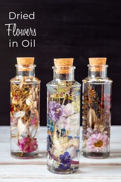 three glass bottles filled with dried flowers in oil