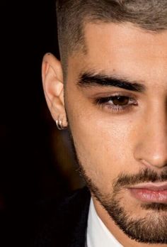 a close up of a person wearing a suit and tie with an earring on