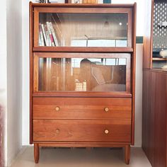 a wooden cabinet with glass doors and drawers