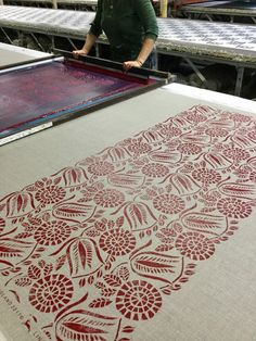 a man standing in front of a table with an intricately designed cloth on it