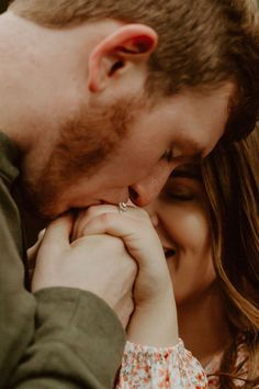 a man and woman holding each other close to their foreheads as they look at each other