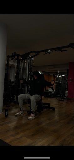 a man squatting on a bench in a gym with an exercise machine behind him