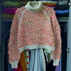 an open closet filled with clothes and sweaters