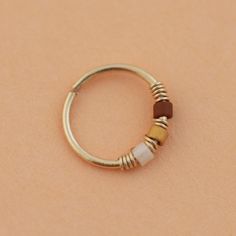 a close up of a gold ring with beads on it's end and a brown bead in the middle