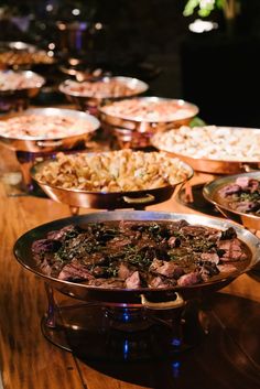 a table topped with lots of different types of food on top of metal pans