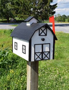 a white and black mailbox sitting on top of a wooden post in the grass