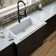 a white kitchen sink sitting on top of a counter next to a window with a faucet