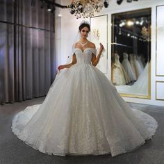 a woman standing in front of a dress on display at a bridal showroom