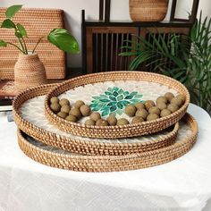 three wicker trays with flowers on them are sitting on a white tablecloth