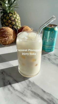 a pineapple drink next to a can of coconut soda on a marble counter top