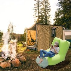 a woman sitting on a bean bag chair next to a campfire