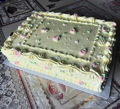 a cake with frosting and decorations on it sitting on a glass platter in front of a rug